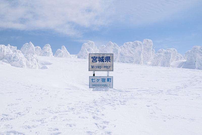 '雪に覆われた宮城県七ヶ宿町の県境看板と足跡'