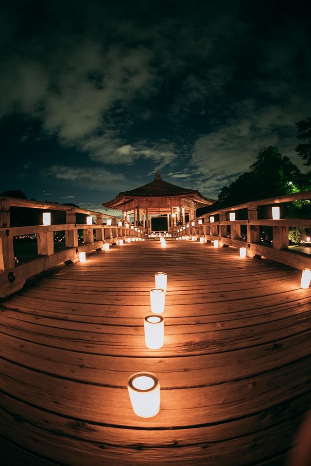 '奈良の燈花会で夜間ライトアップされた木造橋と一列に並ぶろうそく'