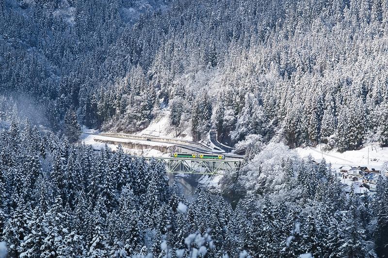 冬の山岳地帯を行き来する列車が通過する雪景色の鉄道橋梁