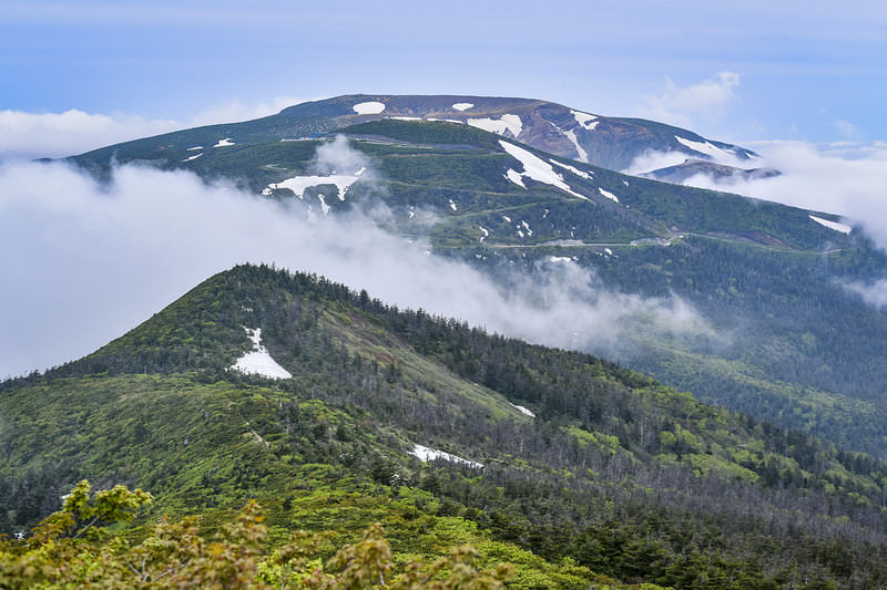 '雲を纏う蔵王連峰の登山道から眺める重なり合う山々の景色'