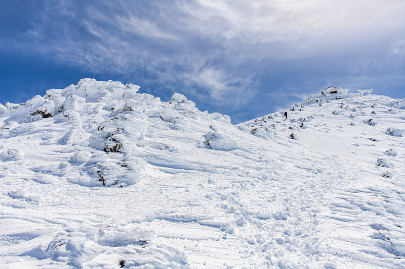 '冬の乗鞍岳山頂を目指す登山者と青空の雲、積雪景色'