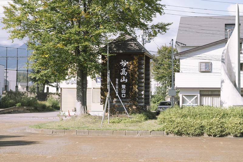 '駅前の妙高山登山口の標識と樹木、新潟県の観光地'