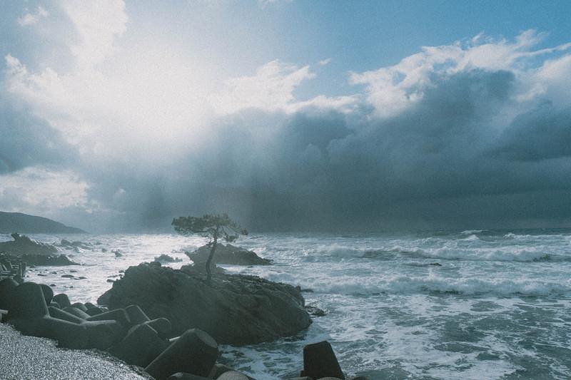 '黒雲と青空が対比する荒波の海岸線'