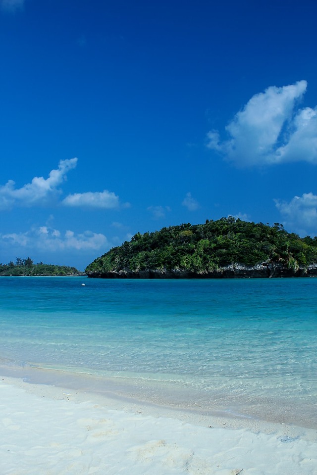 '沖縄の青い海と緑の島、白い砂浜とリゾートの風景'