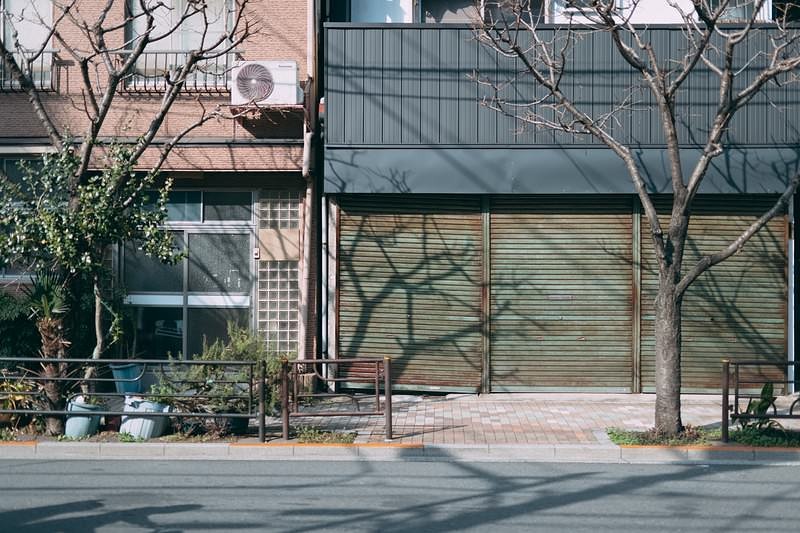 'シャッターの下りた店舗の軒先と歩道の街並み'